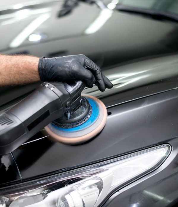 Ein Mann poliert ein Auto mit einer Poliermaschine