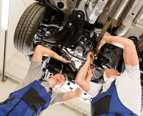 Zwei Mechaniker arbeiten unter einem angehobenen Auto