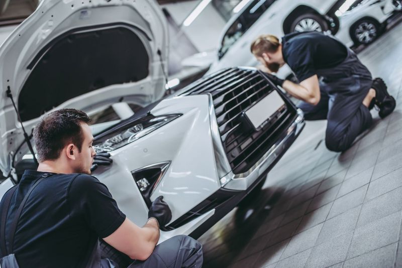 Zwei Männer prüfen und reparieren ein weißes Auto